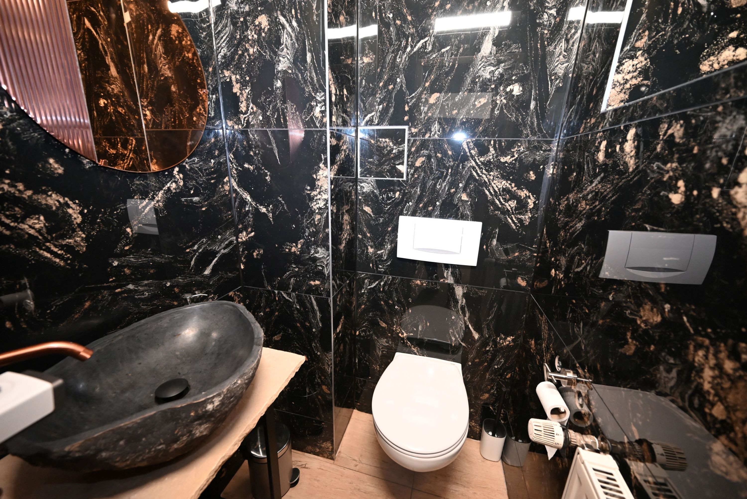 A bathroom with a black marble sink, a white toilet, and a mirror.
