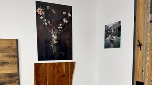 Een eetgedeelte met een houten tafel, twee stoelen en een schilderij erboven.