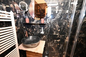 A bathroom with a black marble sink, a mirror, and a towel rack.