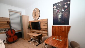 Een kamer met een houten bureau, een televisie, een klok, een viool en een schilderij.