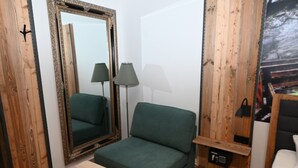 Een kamer met een groene bank, een klein tafeltje, een spiegel en een lamp.