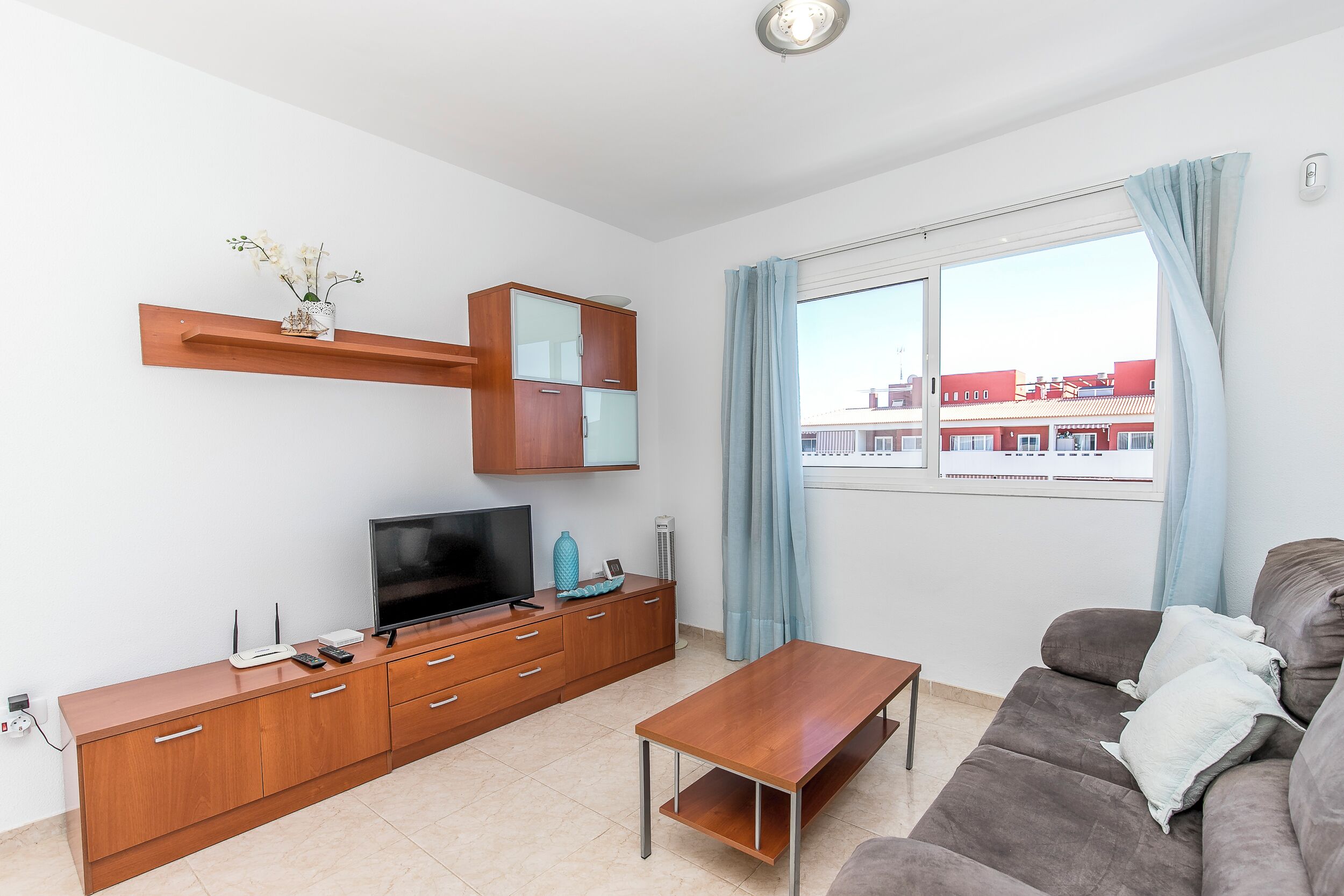 A modern living room with a flat-screen TV, wooden cabinet, and a sofa.