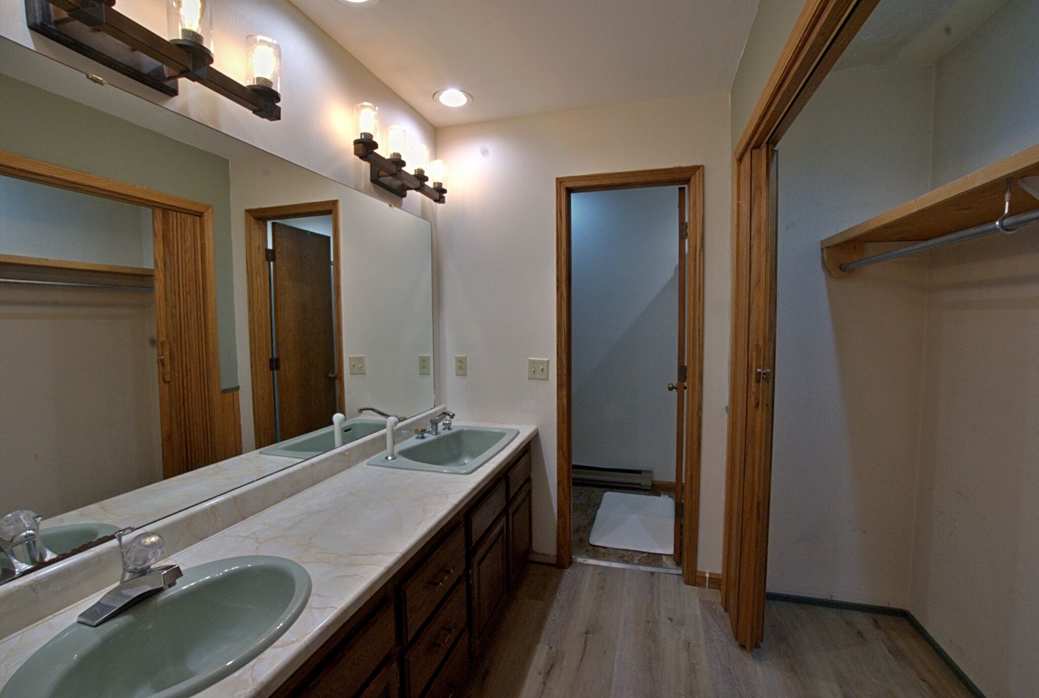 A bathroom with two sinks, a large mirror, wooden cabinets, and a shower area.