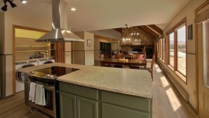 Een moderne keuken met een centraal eiland, inbouwapparatuur en een wand van natuursteen.