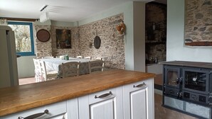 Une cuisine avec un mur en pierre, un comptoir en bois et une cuisinière.