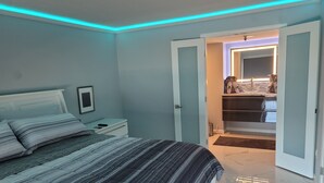 Un dormitorio moderno con cama, mesitas de noche y vestidor.