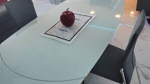 Una cocina moderna con una isla grande, un comedor con mesa de vidrio y un televisor montado en la pared.