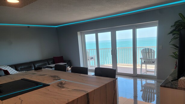 Una sala de estar moderna con una mesa de centro de mármol, un sofá y un balcón con vista al mar.