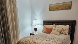A bedroom with a bed, a nightstand, a lamp, a painting, and curtains. - Charming 3-bedroom house in  wonderful and fascinating Berlin, MD. (Berlin)