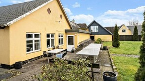 A yellow building with a tiled roof, a covered outdoor seating area, and a lawn. - Knudstrup Kro & Hotel (Kjellerup)