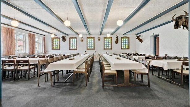 A large dining hall with long tables and chairs, high ceilings with exposed beams, and mounted animal heads on the walls. - Knudstrup Kro & Hotel (Kjellerup)
