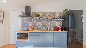 Una cucina moderna con forno integrato, frigorifero in acciaio inossidabile e una parete di fondo decorata.