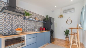 Una cucina moderna con mobili blu, forno integrato, frigorifero nero e piano di lavoro in legno.