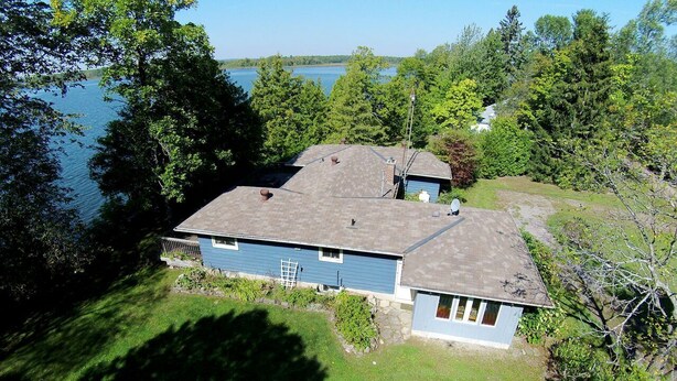 Une maison avec un toit en pente, une cour clôturée et une vue sur un lac.