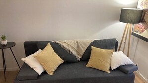 A dark grey sofa with three cushions, a small side table with a plant, and a floor lamp. - Independent Cozy Room (Montpellier)