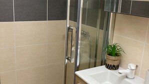A bathroom with a glass shower enclosure, a sink with a mirror above it, and a potted plant on the counter. - Independent Cozy Room (Montpellier)