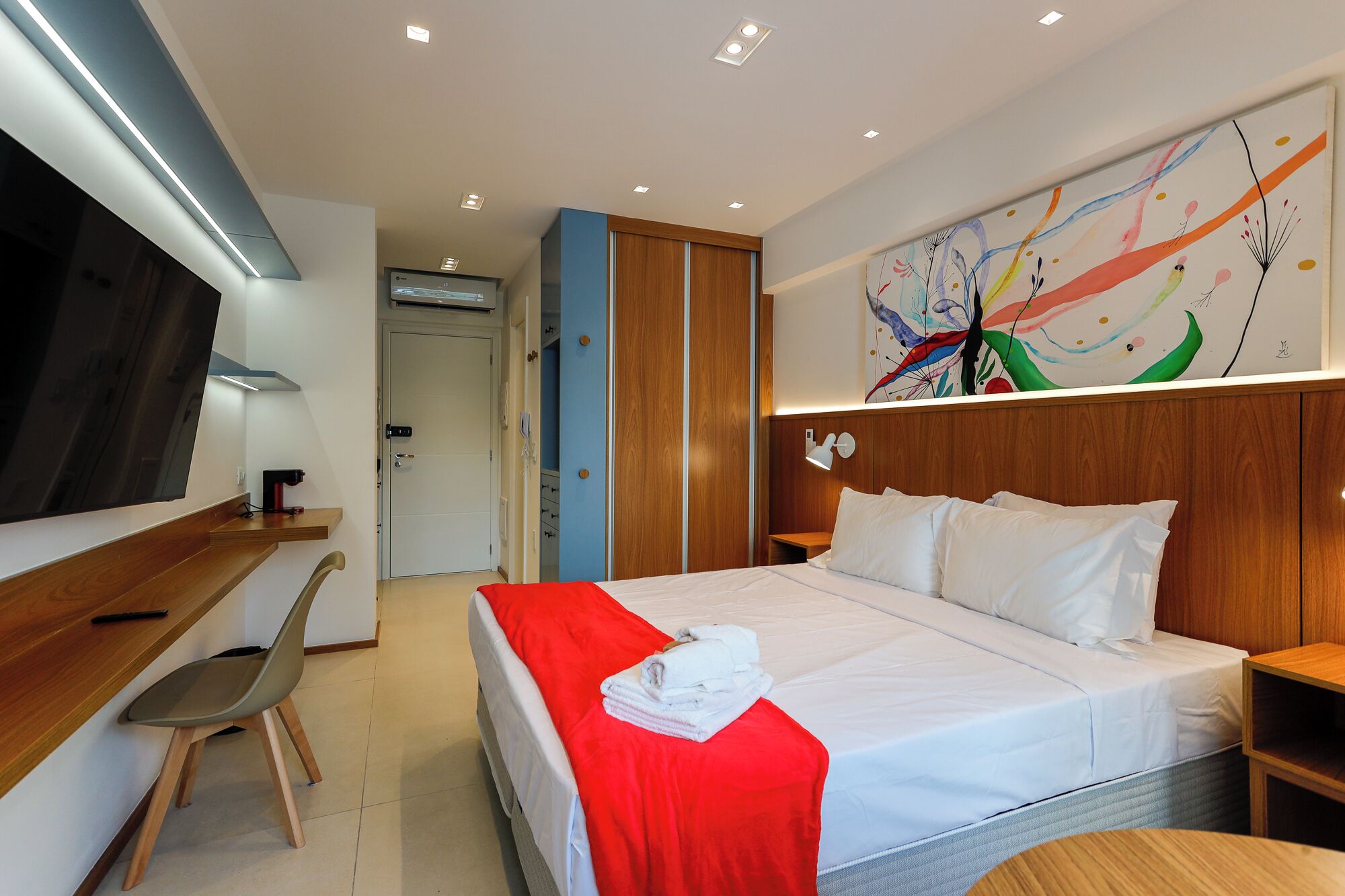 A modern hotel room with a bed, a desk, and a chair.