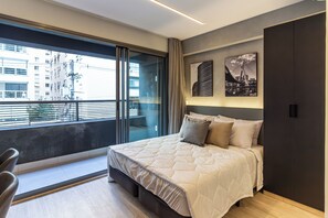 A modern bedroom with a large bed, a sliding glass door to a balcony, and artwork on the wall. - 360 Oscar Itaim (São Paulo)