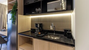 A modern kitchen with a built-in coffee maker, a sink, and a black countertop. - 360 Oscar Itaim (São Paulo)