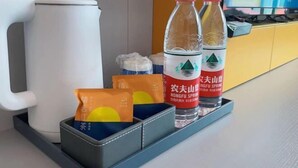 Una zona de cocina con un hervidor blanco, dos botellas de agua y una bandeja con bolsitas de té.