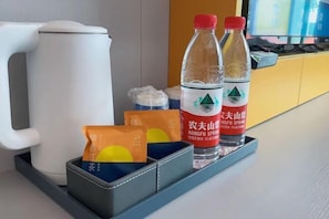 Una zona de cocina con un hervidor blanco, dos botellas de agua y una bandeja con bolsitas de té.