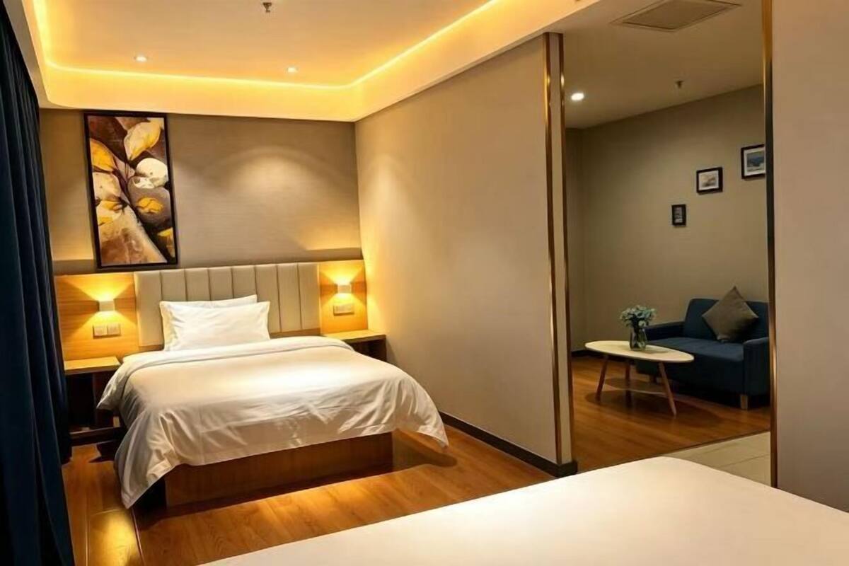 Quarto de hotel moderno com cama, abajures, um sofá e uma pequena mesa.