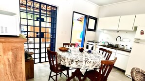 Un coin repas avec une table ronde, six chaises et un paravent bleu.