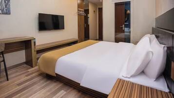 A hotel room with a bed, a desk, a television, and a wardrobe.