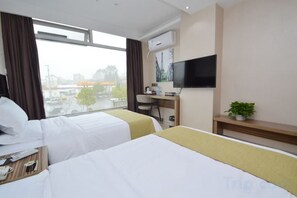 A hotel room with two beds, a desk, a TV, and a window with a city view. - Durian Candy Hotel (Longhua Road Subway Station Jiangpu Bus Terminal Branch) (Nanjing)