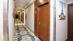 A hotel hallway with patterned flooring, wooden doors, and a wall-mounted picture of the Eiffel Tower. - Durian Candy Hotel (Longhua Road Subway Station Jiangpu Bus Terminal Branch) (Nanjing)