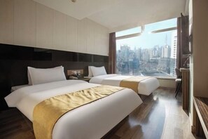 Une chambre d’hôtel avec deux lits, une vue sur la ville et une grande fenêtre.