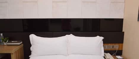 Une chambre d’hôtel équipée d’un lit, d’une table de chevet et d’un téléphone fixé au mur.