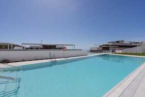 Ein klares Schwimmbecken ohne Personen, umgeben von modernen Gebäuden und blauem Himmel.