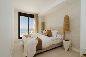 A bedroom with a bed, a small bedside table, a window with a view, and a hanging light fixture.
