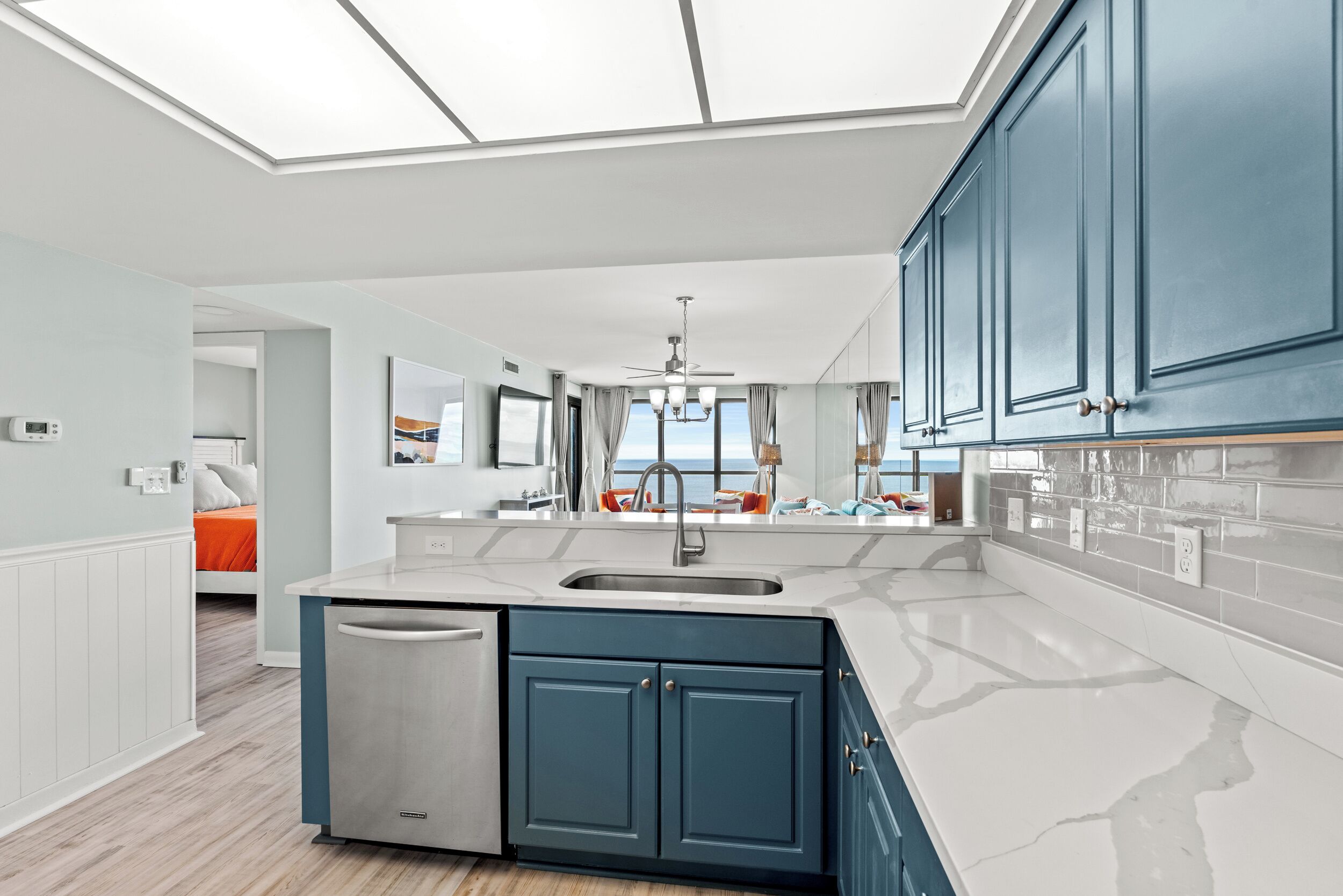 Une cuisine moderne dotée d’un lave-vaisselle encastré, d’un grand îlot central avec un évier et de meubles de couleur bleue.