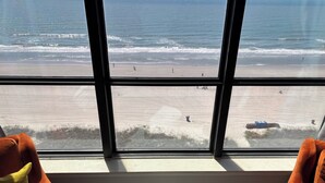 Ein Zimmer mit großem Fenster und Blick auf einen Strand.