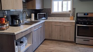 Une cuisine moderne avec des meubles en bois, un four à micro-ondes encastré, une machine à café et un four en acier inoxydable.