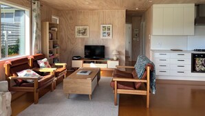Ein modernes Wohnzimmer mit Holzboden, einem Fernseher, einer Couch, einem Couchtisch und einem Bücherregal.