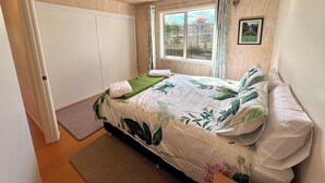 Ein Schlafzimmer mit Bett, Fenster, Tür und einem kleinen Teppich.