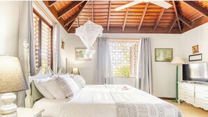 A bedroom with a bed, a TV, a nightstand, and a window with curtains. - Charming 3-bedroom villa in enchanting Trelawny with AC, WiFi (Trelawny)