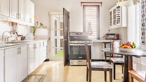 A kitchen with white cabinets, a stove, a microwave, and a dining area with a table and chairs. - Charming 3-bedroom villa in enchanting Trelawny with AC, WiFi (Trelawny)