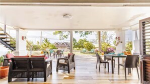 An open-air covered patio with wicker furniture, a dining table, and potted plants. - Charming 3-bedroom villa in enchanting Trelawny with AC, WiFi (Trelawny)