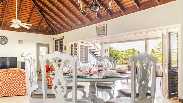 A dining area with a round table, white chairs, and a ceiling fan. - Charming 3-bedroom villa in enchanting Trelawny with AC, WiFi (Trelawny)