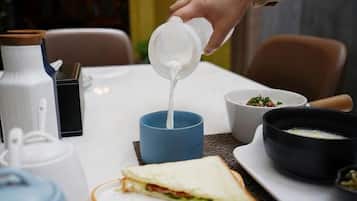 Una persona vertiendo un líquido blanco en una taza azul.