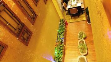 Un pasillo estrecho con puertas de madera, una mesa con sillas y un arreglo de plantas.
