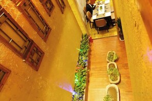 A narrow corridor with wooden doors, a table with chairs, and a plant arrangement. - Dengnilai Inn (Fenghuang County)