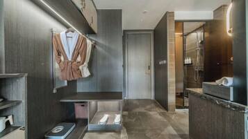 A modern bathroom with a marble floor, a towel rack with robes, a scale, and a shower area.