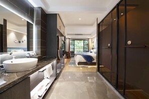 A modern hotel room with a large bathroom vanity, a bed with a blue accent, and a view of the outdoors through large windows. - Dengnilai Inn (Fenghuang County)