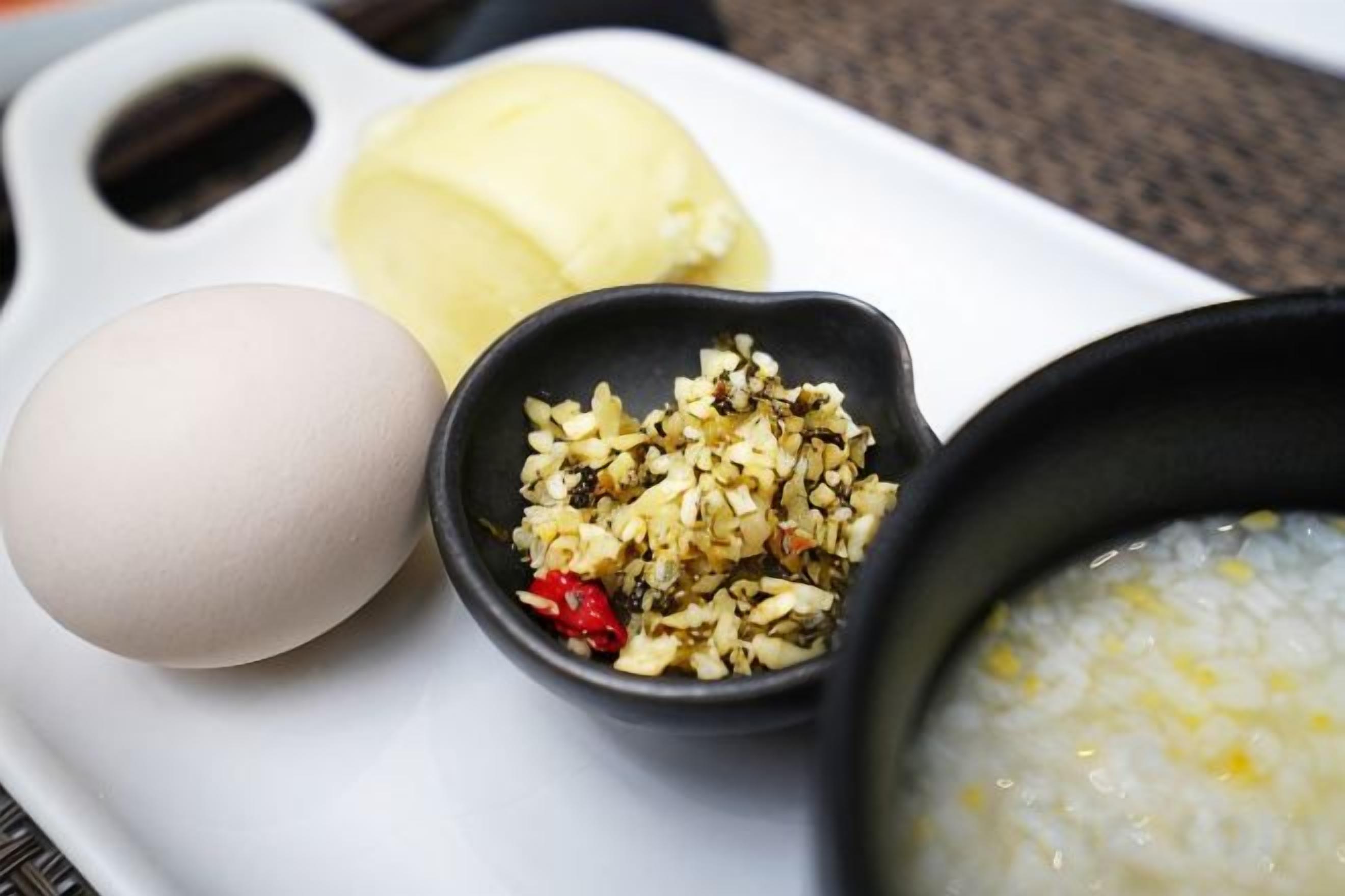 A plate with a boiled egg, a bowl of rice, and a small dish of pickled vegetables.