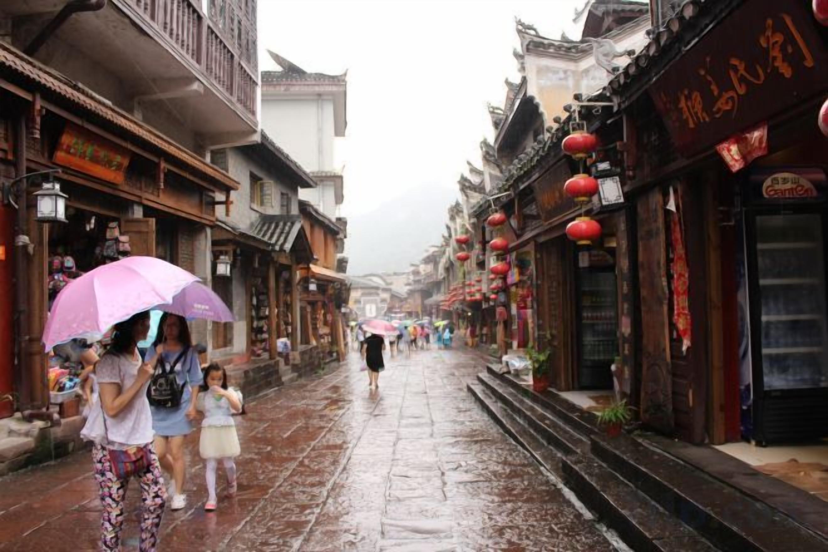 A wet street in a traditional town with buildings featuring wooden facades and red lanterns.